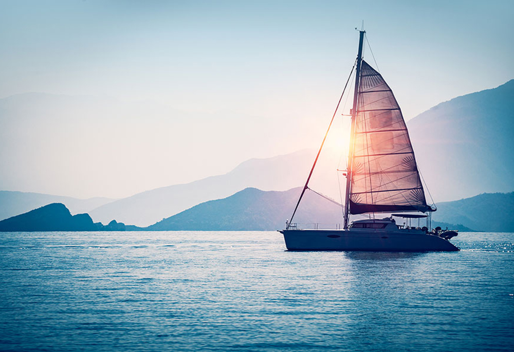 Sailboat in the sea in the evening sunlight over beautiful big m